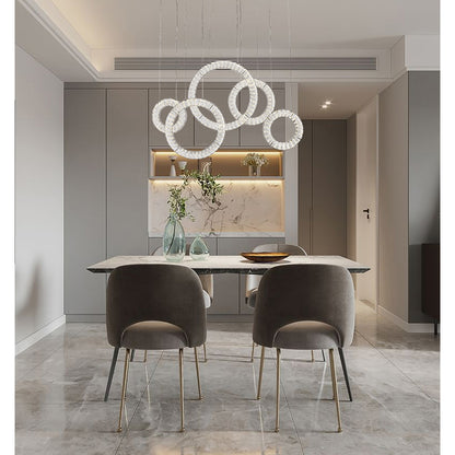 Modern 5-ring Chrome Ring crystal chandelier suspended in a staggered cloud formation over a minimalist dining table.