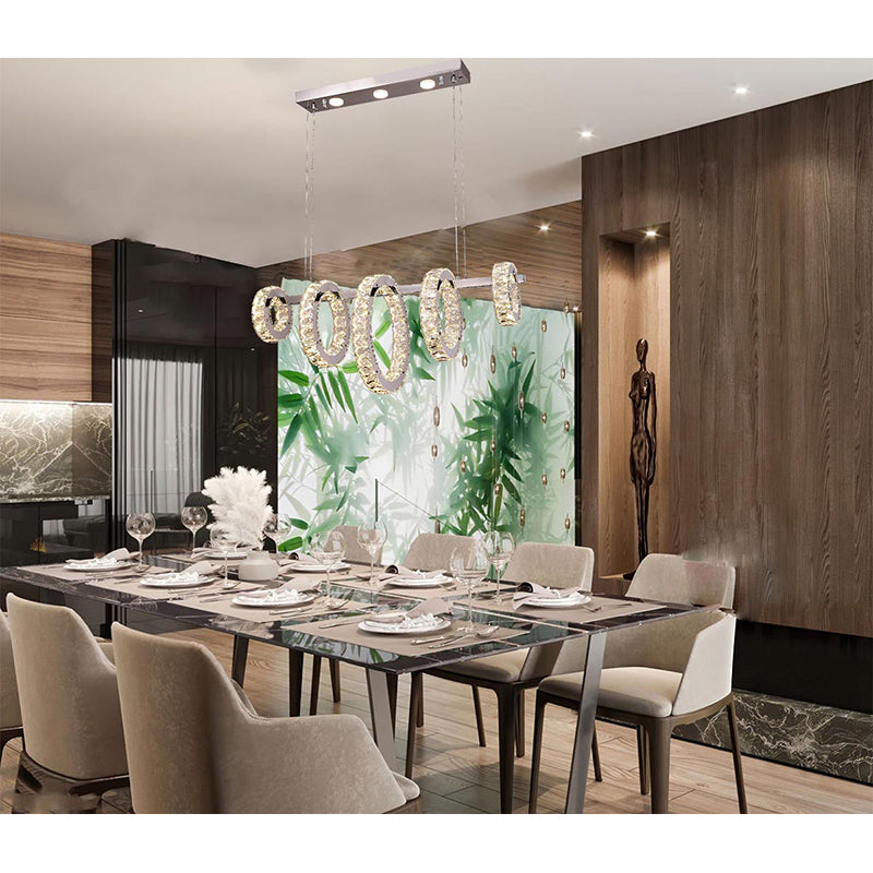 Chrome 5-ring linear chandelier suspended over a modern dining table, showcasing its suitability for dining area lighting.