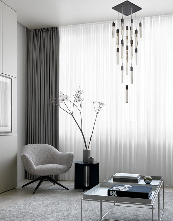 The ADS05C25B 25-light black gun metal chandelier suspended in a dramatic, dark-themed foyer with a curved staircase, creating a high-contrast focal point.