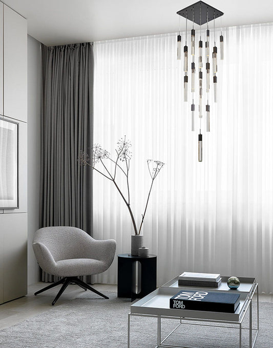 The ADS05C25B 25-light black gun metal chandelier suspended in a dramatic, dark-themed foyer with a curved staircase, creating a high-contrast focal point.
