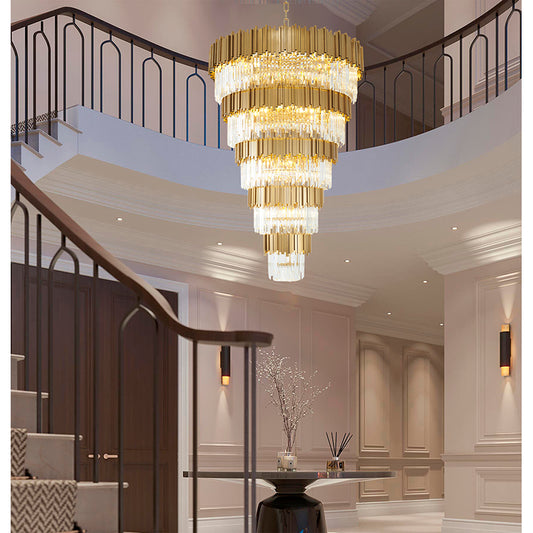 63-inch Brushed Brass Cascading crystal chandelier installed in a grand two-story foyer with a curved staircase.