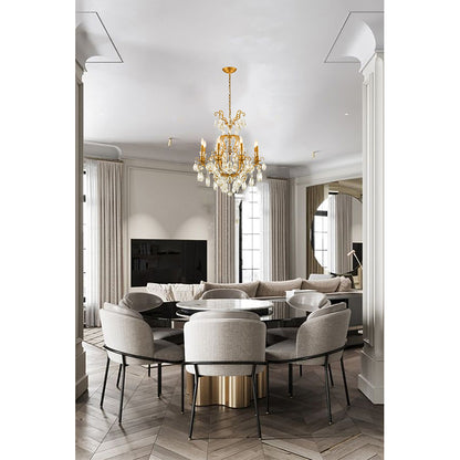 2-tiered brass crystal chandelier hanging in a modern white dining room above a round marble table and grey chairs.