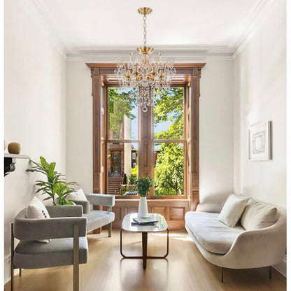 Traditional brass candelabra chandelier centered in a sunlit living room with hardwood floors.