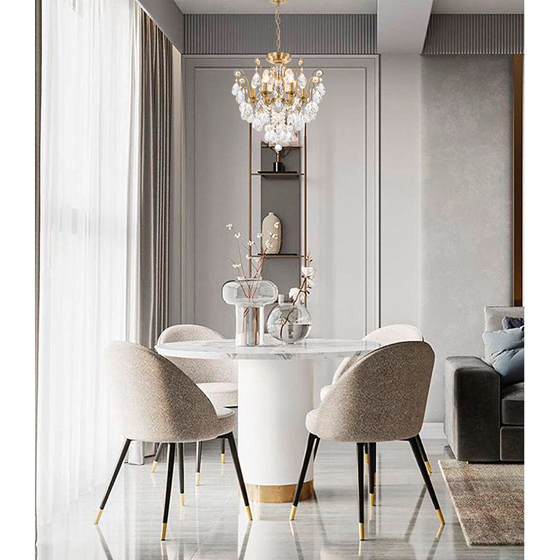 21-inch brass crystal chandelier hanging in a bright dining area with a marble table and upholstered chairs.