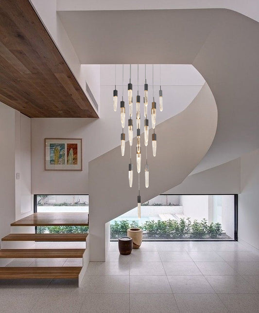 The ADS16C25B 25-light black gun metal chandelier suspended in the center of a white spiral staircase, creating a dramatic, contemporary focal point.