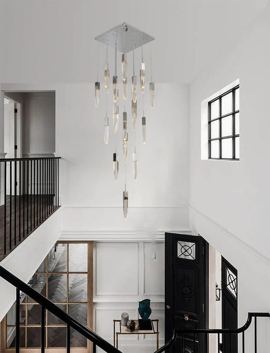 The ADS16C25CH 25-light chrome chandelier hanging in a bright, modern two-story foyer with a black railing and white walls.