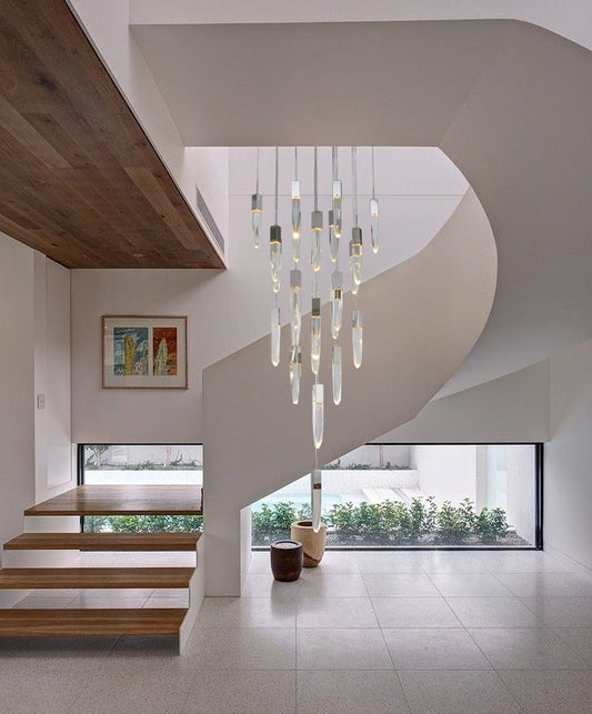 The ADS20C25CH 25-light chrome chandelier suspended in the center of a white spiral staircase, creating a dramatic focal point in a modern, open-concept home.