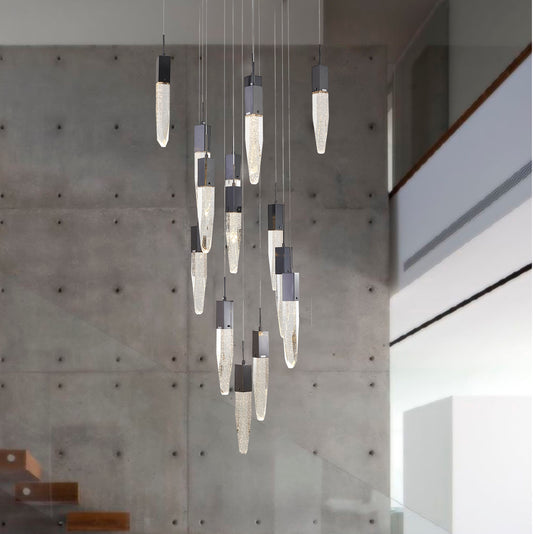 The black gun metal chandelier hanging in a high-ceilinged modern space with a grey concrete feature wall. 