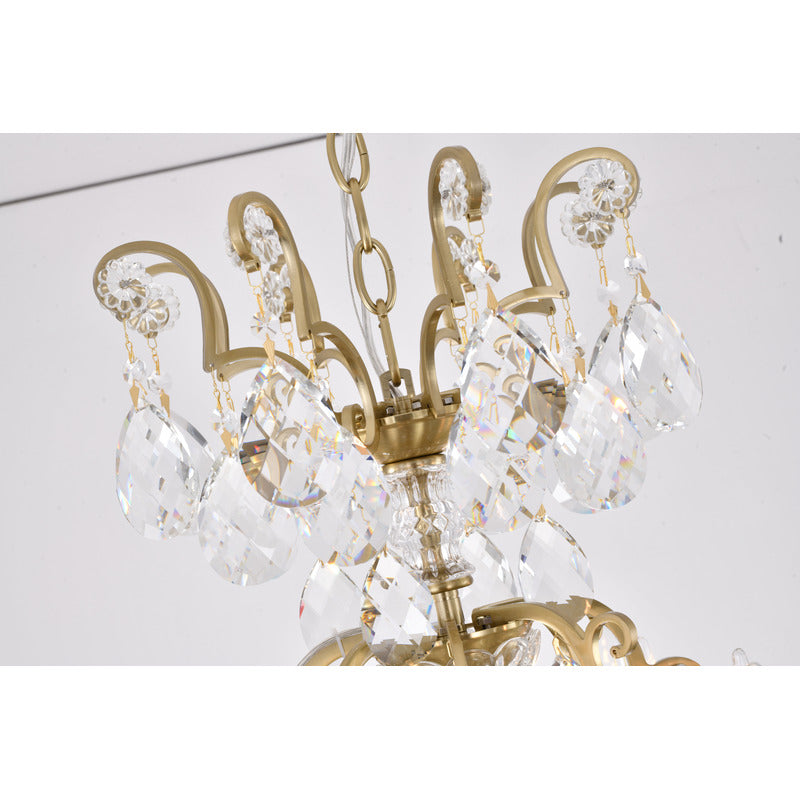 Close-up of the upper tier of the brass chandelier featuring scrollwork arms and hanging crystal prisms.