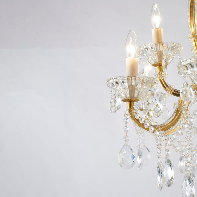 Angle shot of the brass chandelier's outer arms and candle-style bulbs against a clean neutral background.